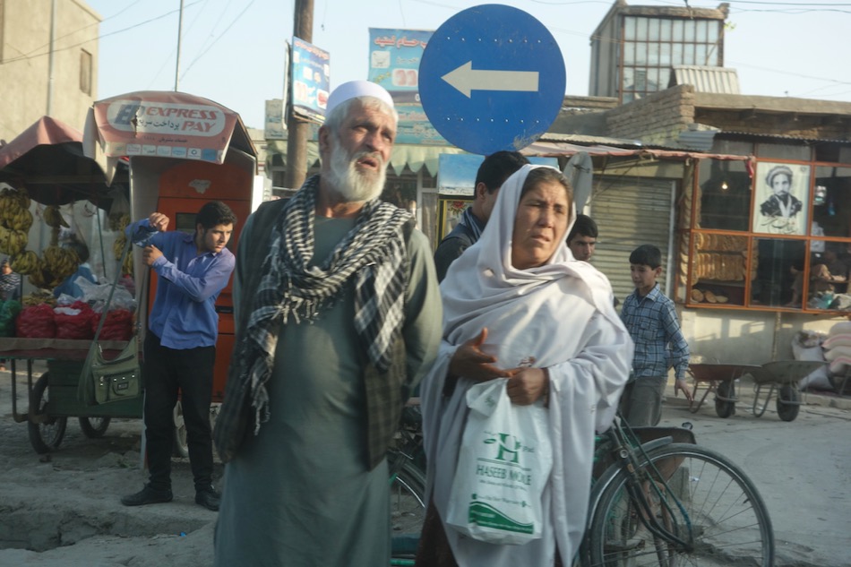 A couple waits to cross Airport Road, early in the morning.