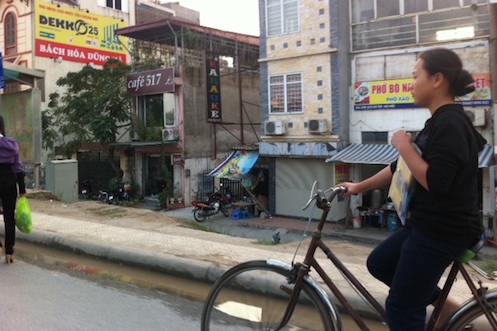 A woman bikes on the airport road to Hanoi