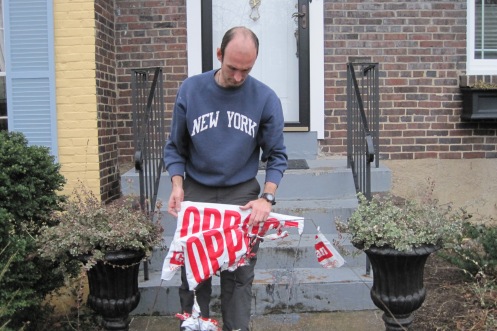 Glen Harrison examines a burned sign on his doorstep