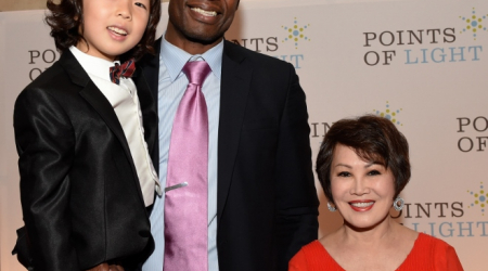 Basketball great Dikembe Mutombo lifts up prodigy cellist Justin Yu as honorary co-chair Yue-Sai Kan is amused by the heights.