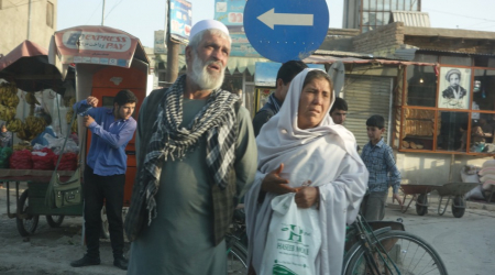 A couple waits to cross Airport Road, early in the morning.