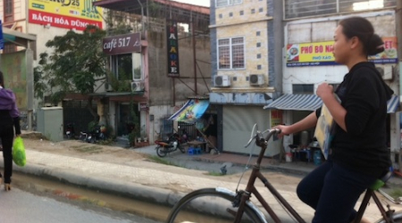 A woman bikes on the airport road to Hanoi